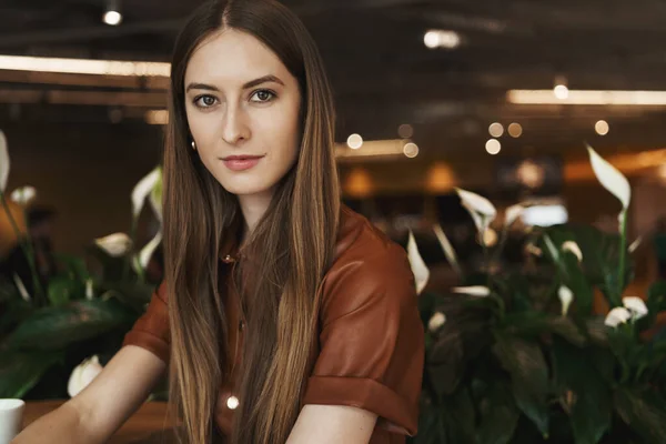 Primer plano retrato de la joven mujer de negocios moderna en vestido marrón con estilo, sentado en la cafetería, beber café, disfrutar de la conversación, día libre. Gerente de restaurante hablando con los empleados, sonriendo agradablemente —  Fotos de Stock