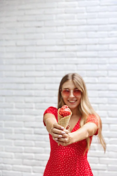Léto, krása a dovolená. Vertikální záběr šťastné atraktivní blond žena těší slunečný den venku, natáhnout ruce se zmrzlinou a široce se usmívat, vyjádřit radost a radost — Stock fotografie