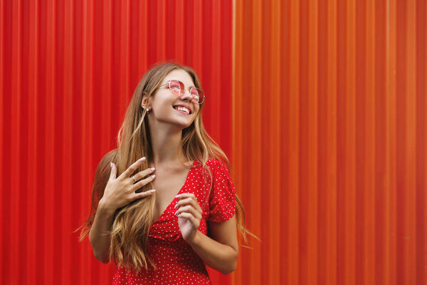 Summer, lifestyle and beauty concept. Portrait of carefree, relaxed young woman traveller, lady enjoying trip on vacation, look away, smiling standing against red building wall, explore city Stock Image
