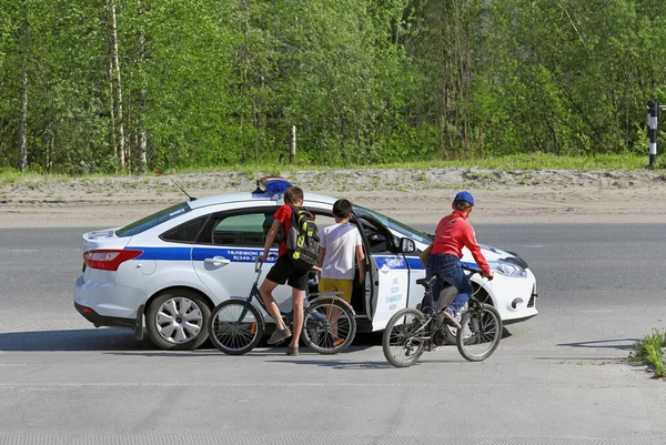 Trafik polisi arabası ve yazın bisikletli çocuklar. — Stok fotoğraf