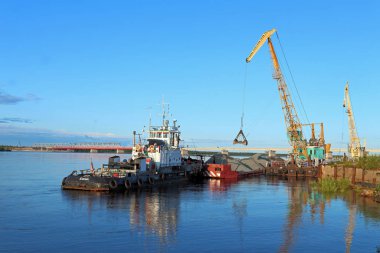 Rıhtımda mavnalı bir römorkör ve yüzen bir vinç. 