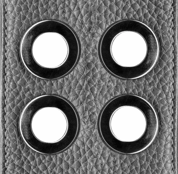 Quatre anneaux décoratifs en acier sur fond cuir gris — Photo