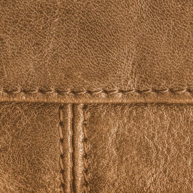sarımsı-kahverengi deri doku dikişleri ile dekore edilmiştir.