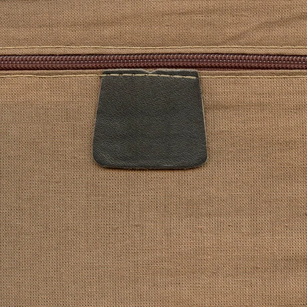 Kahverengi deri etiket, fermuar Tekstil zemin üzerine — Stok fotoğraf