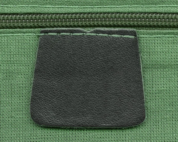Lederetikett, Reißverschluss auf grünem Textilhintergrund — Stockfoto