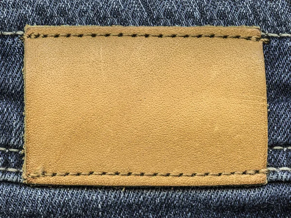 Etykieta jasny brązowy skórzany na tle denim — Zdjęcie stockowe