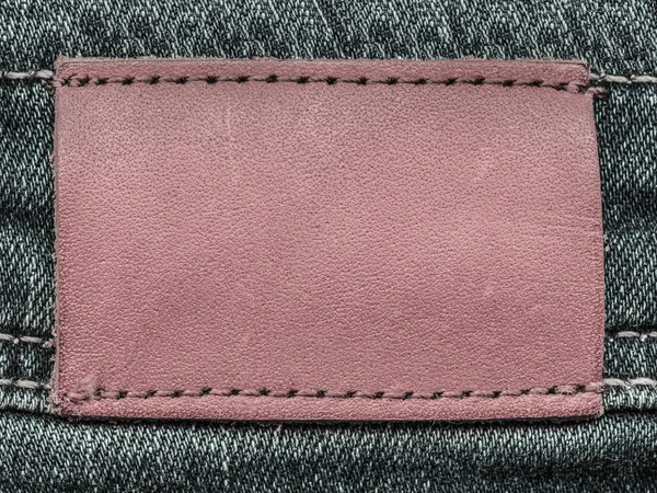 Prázdné načervenalá kůže štítek na pozadí džínovina — Stock fotografie