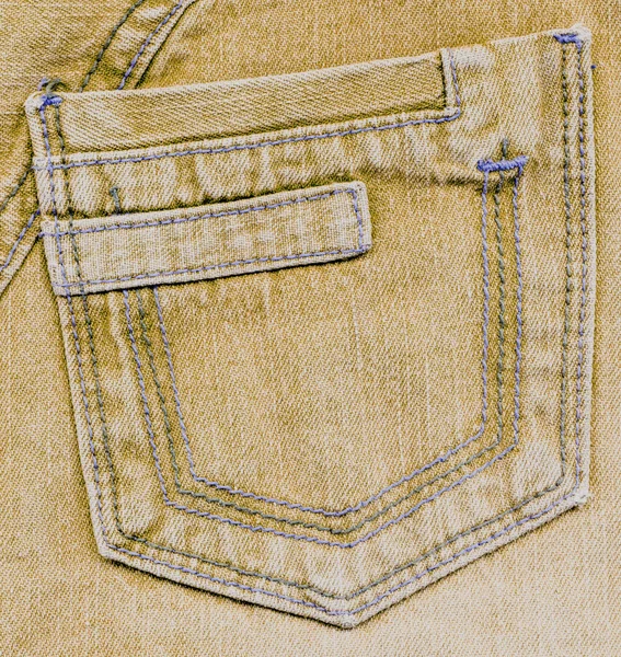 Worn yellow back pocket on denim background — Stock Photo, Image