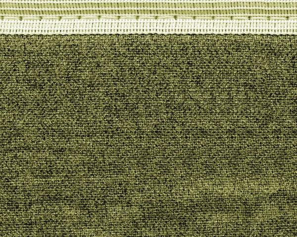 Arka plan gri-yeşil kumaş dikili bir kurdele ile — Stok fotoğraf