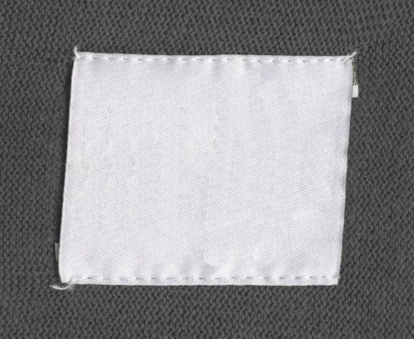 Vieja Etiqueta Tela Blanca Blanco Sobre Fondo Textil Gris —  Fotos de Stock
