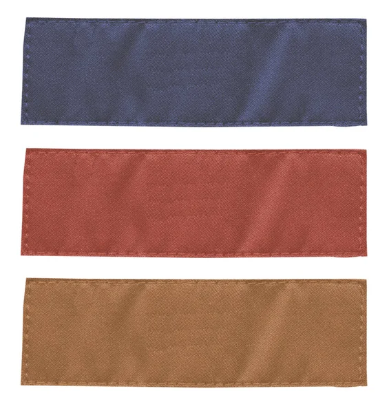 Three blank fabric tags of different colors — Stock Photo, Image