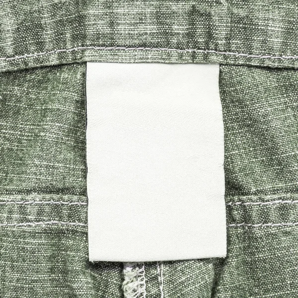 Gri Yeşil Denim Arka Plan Üzerinde Boş Beyaz Kumaş Etiket — Stok fotoğraf