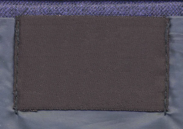 Etiqueta de tecido marrom em branco no fundo têxtil azul — Fotografia de Stock