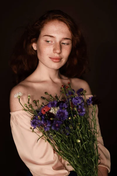 Rödhårig flicka innehav vilda blommor — Stockfoto