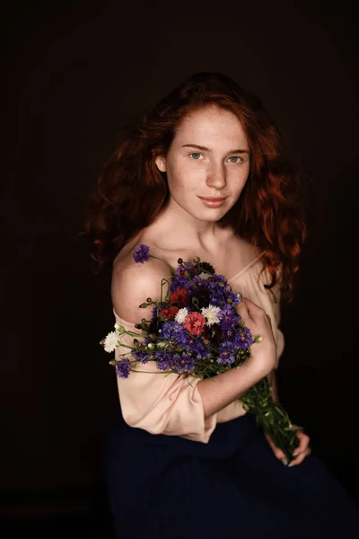 Redhead girl holding wild flowers — Free Stock Photo