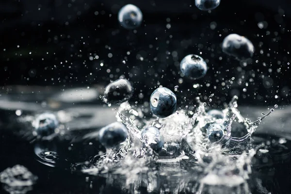 Ripe blueberries dropping in water — Stock Photo, Image