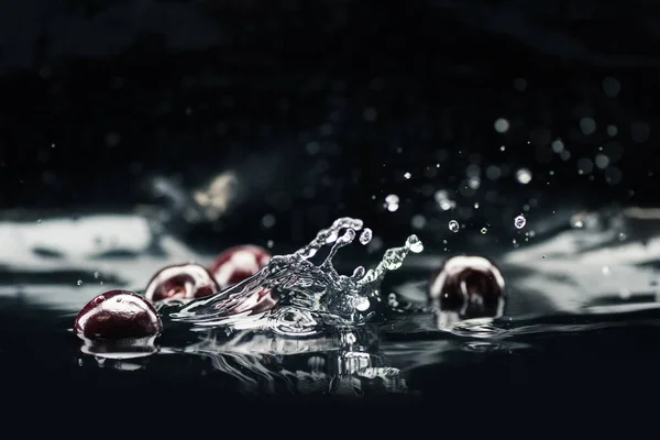 Ripe cherries falling in water — Stock Photo, Image