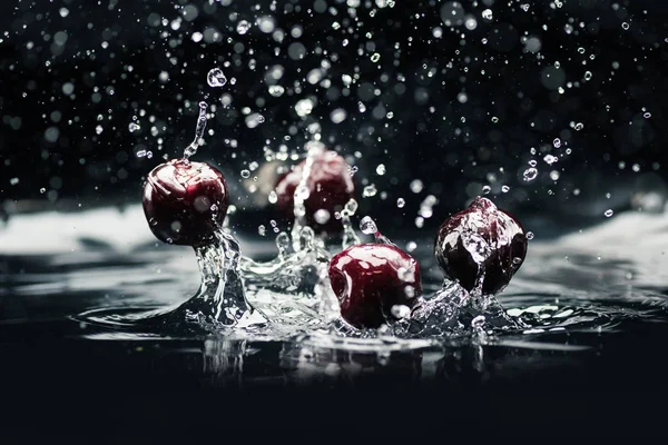 Ripe cherries falling in water — Stock Photo, Image