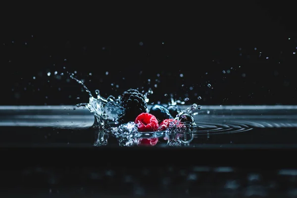 Ripe berries falling in water — Stock Photo, Image