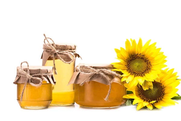 Sunflowers and honey in glass jars — Stock Photo, Image