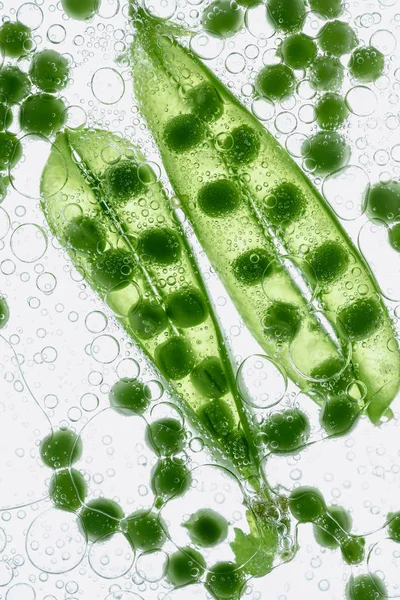 Green peas floating in water — Stock Photo, Image