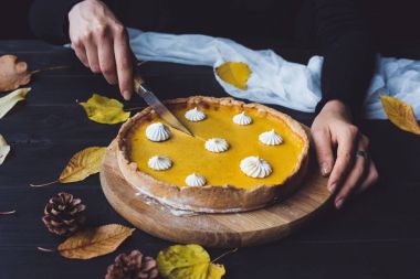 Female hands cutting pumpkin pie clipart