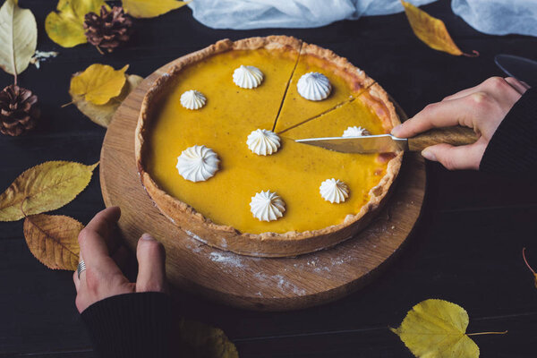 Female hands cutting pumpkin pie