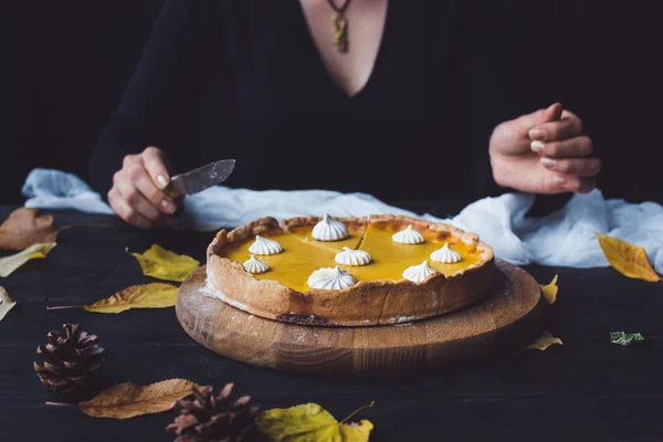 Torta di zucca sul tavolo e donna con coltello — Foto Stock