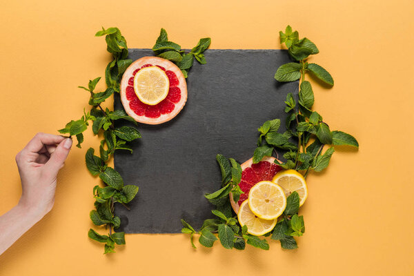 hand with mint leaves, citrus slices 