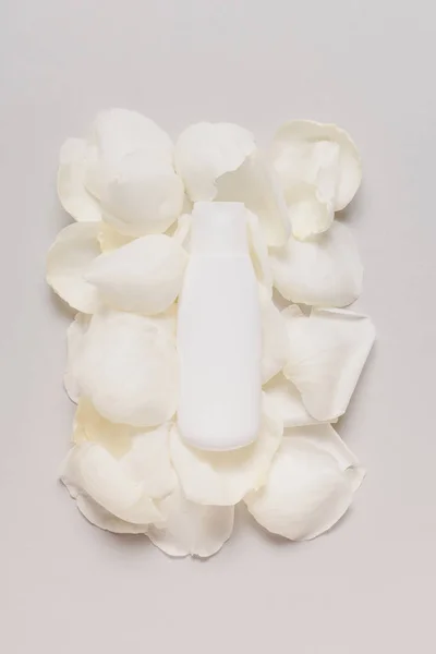 Bottle of lotion on petals — Stock Photo, Image