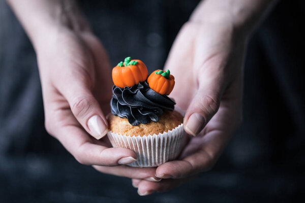 person holding halloween cupcake