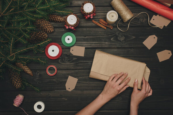 женщина упаковывает рождественский подарок
