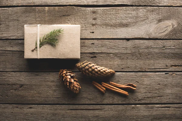 Presente com cones de pinheiro e paus de canela — Fotografia de Stock