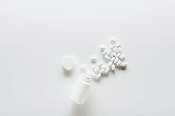 Белые таблетки и контейнер — стоковое фото