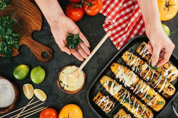 Frau fügt Dill auf gegrilltem Mais hinzu — Stockfoto