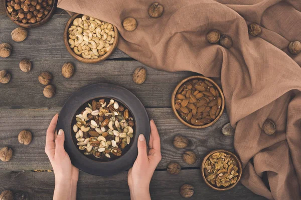 Skål med olika nötter i händer — Stockfoto