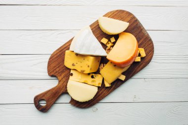 assorted types of cheese on cutting board clipart