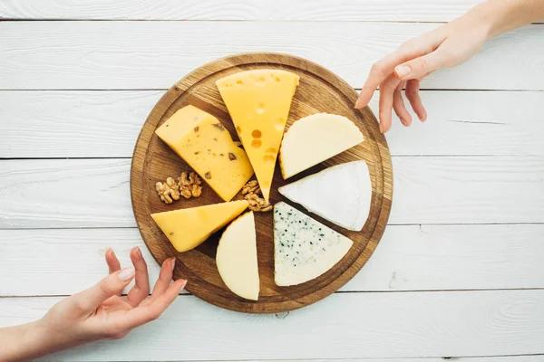 Mãos femininas e tipos arranjados de queijo — Fotografia de Stock