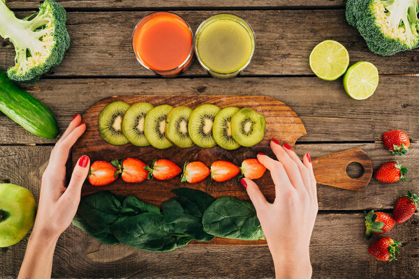 woman and cutting board with fresh vegetables and fruits