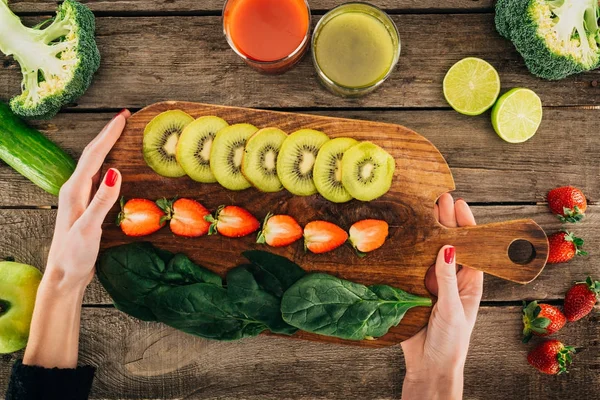 Mulher e tábua de corte com legumes e frutas frescas — Fotografia de Stock