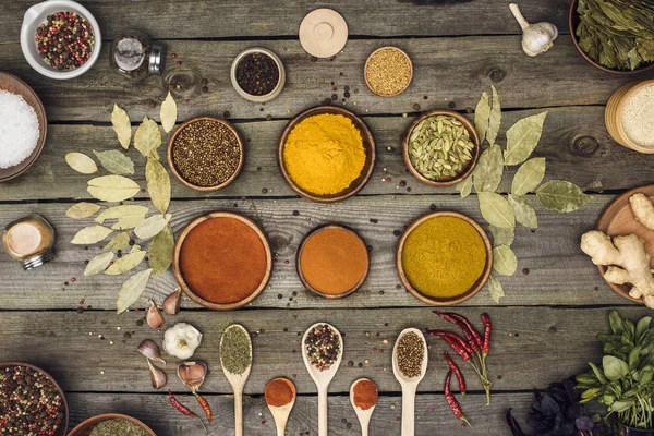 Bowls and wooden spoons with different spices — Stock Photo, Image