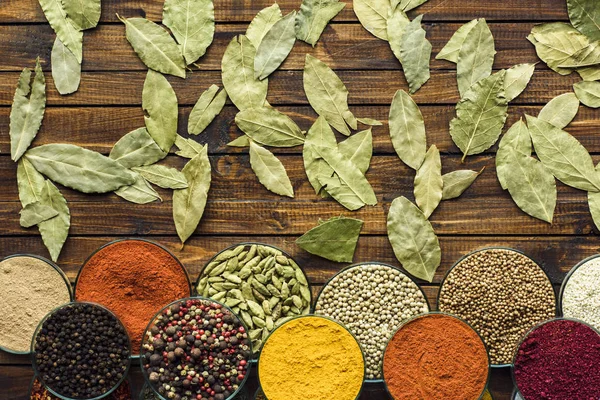 Scattered bay leaves and bowls with spices — Stock Photo, Image