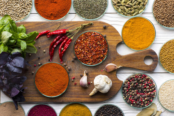 bowls with spices on wooden board and table