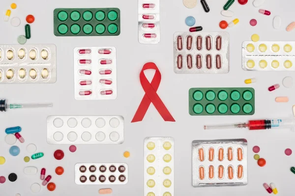 Aids ribbon with pills and syringes — Stock Photo, Image