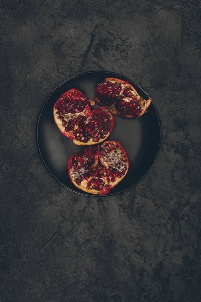 Cut pomegranate on black plate — Stock Photo, Image