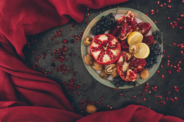 Plate with pomegranates and grapes with lemons — Stock Photo, Image