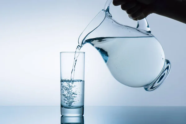 Woman pouring water from jug — Stock Photo, Image