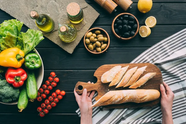 Mãos segurando tábua de cortar com pão — Fotografia de Stock