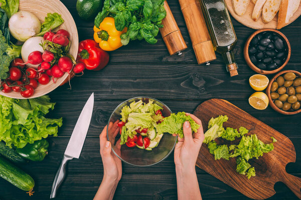 hands holding bowl with salad leaves
