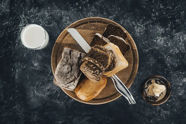 Pão e faca na placa de corte — Fotografia de Stock